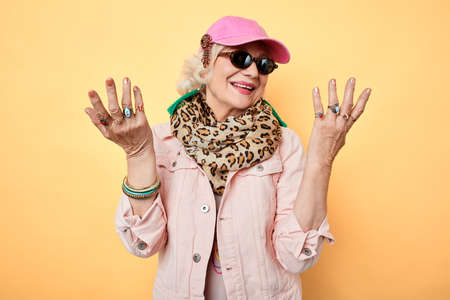stylish happy cheerful woman in sunglasses with raised hands, showing her rings on fingers ,looking...