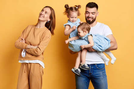 happy young mother standing back to her husband and her little daughters. close up photo. isolated...