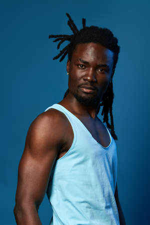 sexy young muscular man in white shirt looking at the camera, isolated blue background, studio shot.の写真素材