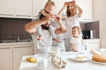 bearded pleasant dad teaching his children to break eggs, close up photo.の写真素材