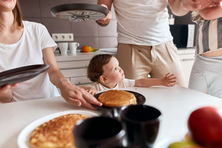 cute little girl waiting for breakfast, kid is looking at her elder sister, who is eating yummy pancakes. close up cropped photo. food conceptの写真素材