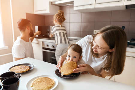 little girl her parents enjoying eating yummy pancakes. close up photo. happiness, weekend, happinessの写真素材