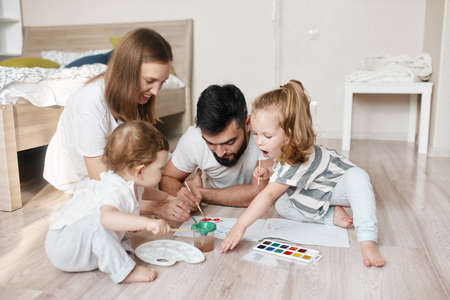 young couple enjoying drawing with children in the bedroom. close up photo. creativity concept, family traditionの写真素材