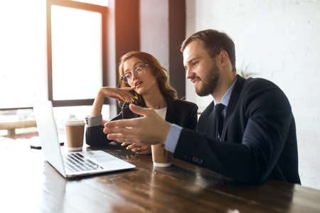 handsome guy explaining his point of view on the problem, thoughtful serious woman touching her lips with finger looking at the screen of laptop. close up photoの写真素材