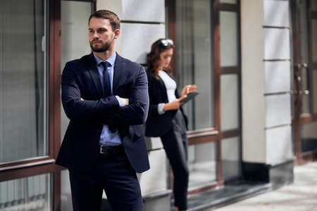 attractive young man in stylish clothes having a rest after business meeting, free time, spare time, close up photo.woman holding tablet in the blurred background of the photoの写真素材