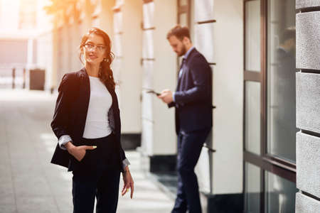 positive awesome woman presenting formal stylish clothes, sale, advert, business, style, people. close up photo, attractive guy working with tablet in the blurred background.busy lifeの写真素材