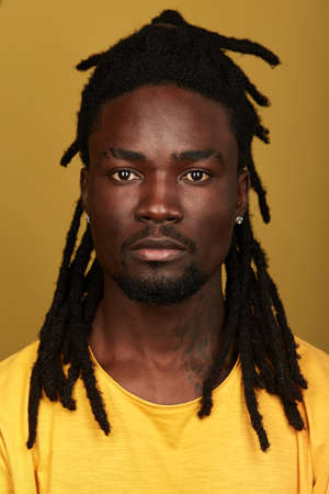 handsome talented rapper looking at the camera, close up photo. isolated yellow background, studio...