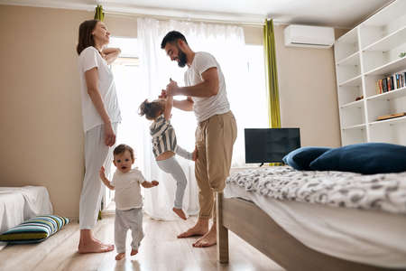 Happy cheerful family having fun in the bedroom, side view photo. happiness, entertainment. copy space, lifestyle, positive feeling and emotionの写真素材