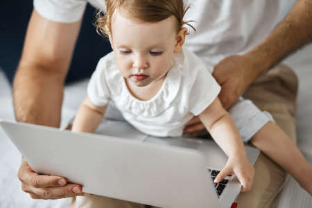 little daughter staing ta the screen of laptop, watching cartoons, close up cropped photo.の写真素材