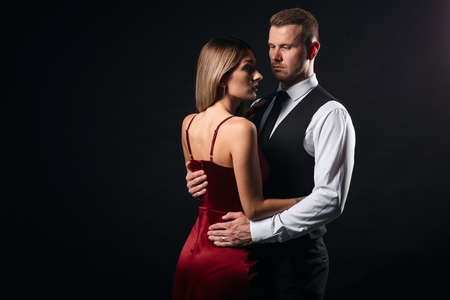 handsome couple in elegant clothes hugging, standing face to face. close up portrait, isolated black background, studio shot.copy space. love, family , relationshipの写真素材