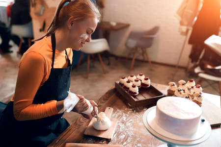 young blonde cook with dirty face is good at decorating dessert. close up side view photo, close up side view photo, girl having fun in the kitchenの写真素材