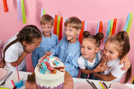 positive little girl and boys waiting for their porsion of dessert, close up photo. isolated pink...