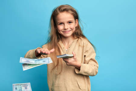 cheerful happy girl throwing money, spending money on nothing, useless things, items. close up portrait, lifestyle, isolated blue background,の写真素材