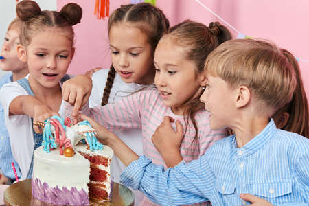 little cute children eating cake with fingers. close up photo. isolated pink background, studio shot