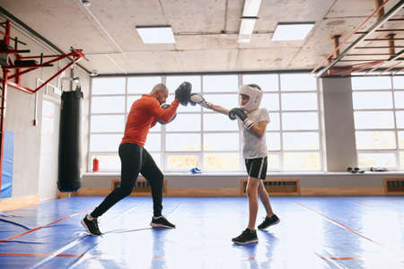 boy learning kickboxing with his father at sport center, full length side view photo. ccopy space....