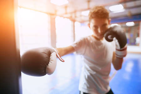 boy hitting the heavy bag in the light room, strength training, close up photo, blurred photo.の写真素材