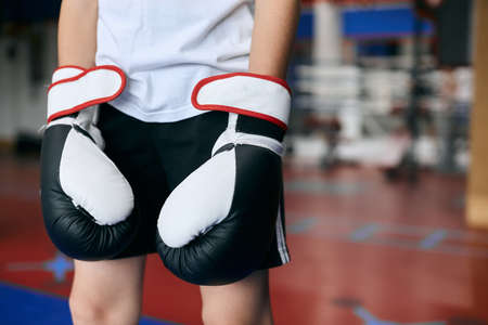 little boy wearing black and white boxing gloves. Copy space. close up cropped photo. clothes, gear...