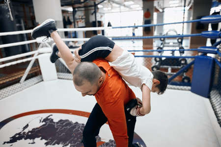 young professional coach showing how to attack the opponent to little boy, teaching him to defense,...