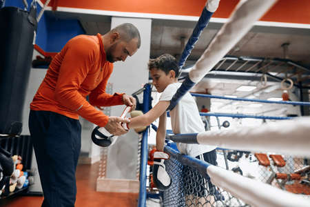 young handsome man helping kid to wear gloves, put on gloves. close up side view photo.の写真素材