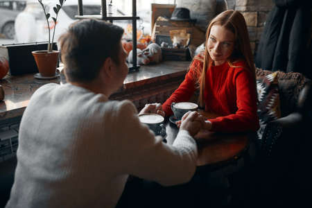 young attractive man expressing his warm feelings, paying compliments to his girlfriend who is wearing red warm sweater, date,affection, close up photoの写真素材