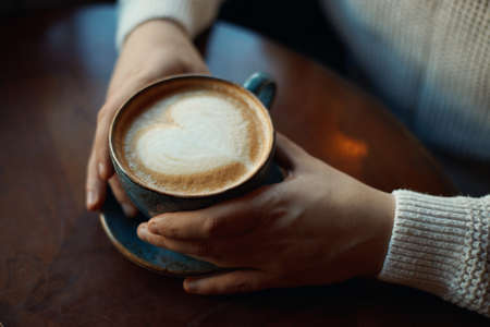 young guy holding a latte with foam of heart shape, who says women are only romantic man is looking for love, never give up. sign, symbol of immortal loveの写真素材