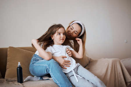 cheerful young blonde woman nd her adorable child sitting on the bed, talking, having fun, sharing secrets. close up photo, friendship, relationshipの写真素材