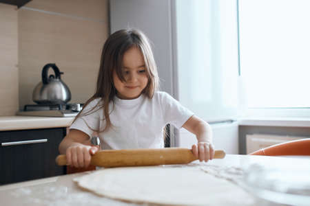 little child holding with rolling pin, close up photo, little young chef, cook, interest, helper, hobbyの写真素材