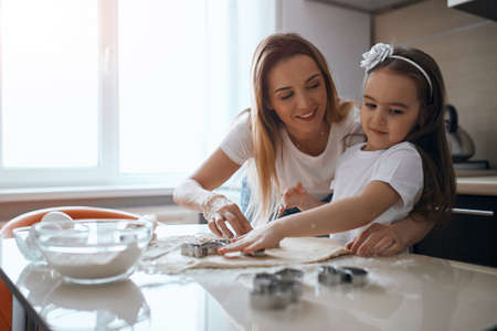 smiling blonde woman helping her child to cut figures. close up photoの写真素材