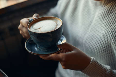 young man enjoying yummy flat white , coffee in the cold winter day. close up side view photo. enjoyment. hobby,break timeの写真素材