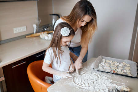 little cute girl spending great time with her mommy in the kitchen. close up side view photo.