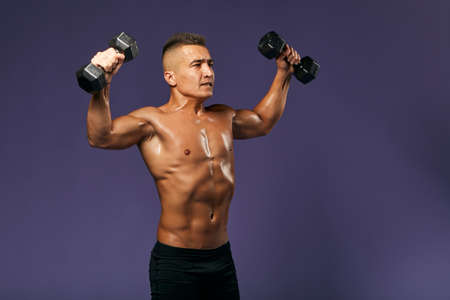 serious man with tensed musculars raising his arms while workout with sport equipment. close up side...