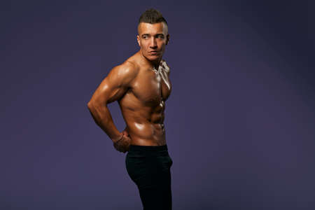 sexy tanned guy with stylish hairdo is being proud of his well-built body, result of active life,...