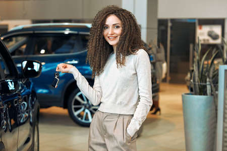 wide varity of second hands vehicles are available at the salon, . dreams come true, close up photo. confident shop assistant offer luxury car. blue car in the background of the photoの写真素材