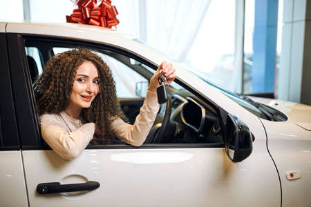 Beautiful young gorgeous woman is close up photokey and smiling while sitting in a new car in...