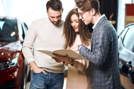 family choosing a car for travel, service. business. close up side view photo.man telling features...