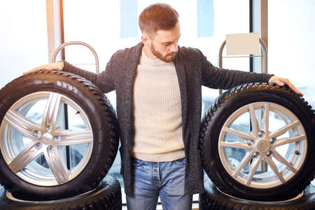 pleasant bearded man touching and choosing for buying a tire in a supermarket shop or DIY department store, close up photo.の写真素材