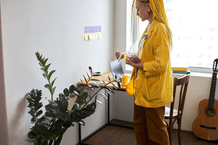Young stylish woman in yellow deads holding color stickers in office. close up side view photo. free...