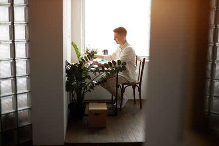 handsome cheerful young man working and typing on laptop at home, full length side view photo.guy playing computer gamesの写真素材
