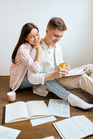 attractive beautifu l woman with long straight hair leaning on her boyfriends shoulder, guy is counting familys badget. vertical shot. close up photoの写真素材