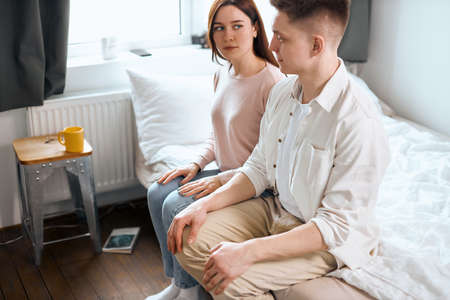 Despaired married couple sitting on the edge of the bed, misunderstaning between couple. close up...