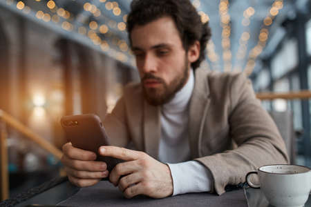 focus on the smart phone blurred image, guy doing shopping online, close up photo. man concentrated on working with gadgetの写真素材