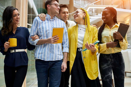 funny young people having fun in the office, telling jokes while walking, young poeple going to have...