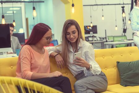 Two woman sitting and working on phoneのeditorial素材