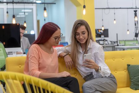 Two woman sitting and working on phoneのeditorial素材