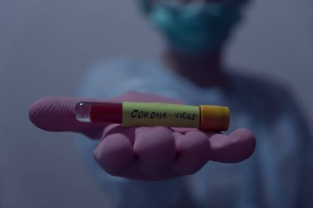 Doctor holding Blood sample of inflected coronavirus covid-19. Doctor wearing respirator mask holding a positive blood test result for the new rapidly spreading Coronavirus,の写真素材