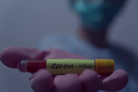 Doctor holding Blood sample of inflected coronavirus covid-19. Doctor wearing respirator mask holding a positive blood test result for the new rapidly spreading Coronavirus,の写真素材