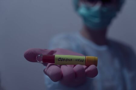 Doctor holding Blood sample of inflected coronavirus covid-19. Doctor wearing respirator mask holding a positive blood test result for the new rapidly spreading Coronavirus,の写真素材