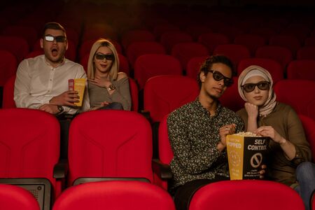 Image of laughing friends sitting in cinema watch film eating popcorn and drinking aerated sweet water.の写真素材