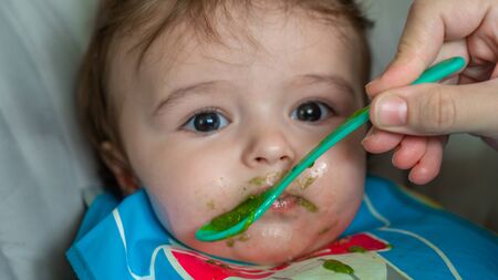 mother feeding her adorable baby boy with a spoonの写真素材