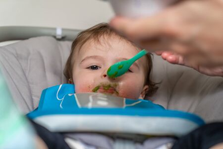 mother feeding her adorable baby boy with a spoon
の写真素材